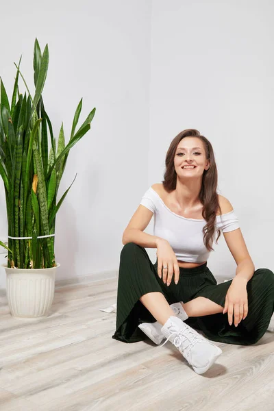 Genç, gülümseyen kız evde yerde oturuyor.