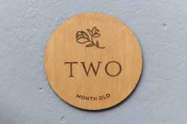 Ahşap yuvarlak tahta üzerinde gri arkaplanda iki yazı var.