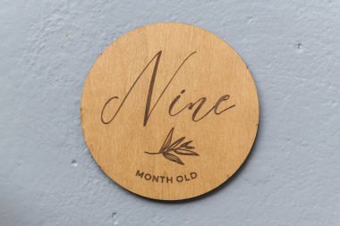 wooden round board with the inscription nine on a gray background