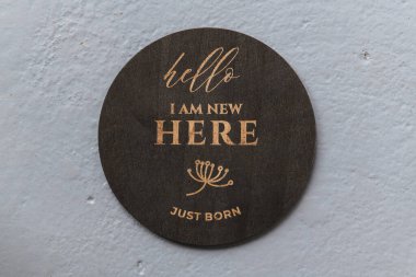 dark wooden round board with the inscription I am new here on a gray background