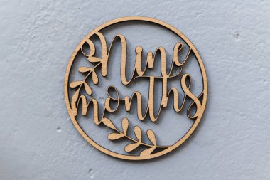 Çocukları fotoğraflamak için gri arka planda uyduları olan açık renkli ahşap bir çember. dokuz ay