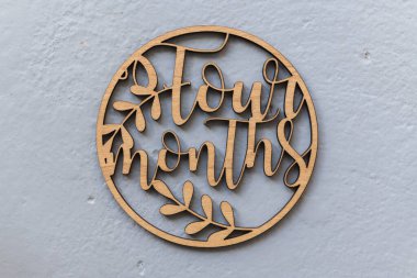 Çocukları fotoğraflamak için gri arka planda uyduları olan açık renkli ahşap bir çember. Dört ay.