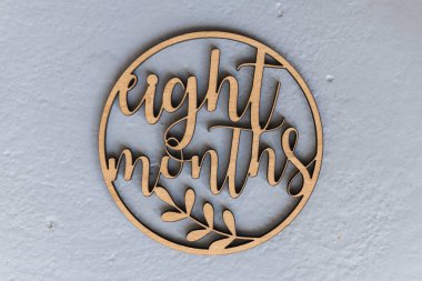 Çocukları fotoğraflamak için gri arka planda uyduları olan açık renkli ahşap bir çember. Sekiz ay.