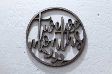 Çocukları fotoğraflamak için gri arka planda uyduları olan koyu ahşap bir çember oyulmuş. 12 ay.