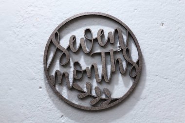 Çocukları fotoğraflamak için gri arka planda uyduları olan koyu ahşap bir çember oyulmuş. Yedi ay.