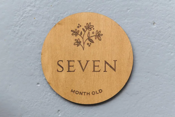 Ahşap yuvarlak tahta üzerinde gri arkaplanda yedi yazılıydı.