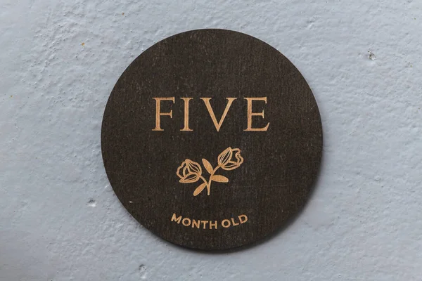 Koyu ahşap yuvarlak tahta üzerinde gri arkaplanda beş yazılıydı.