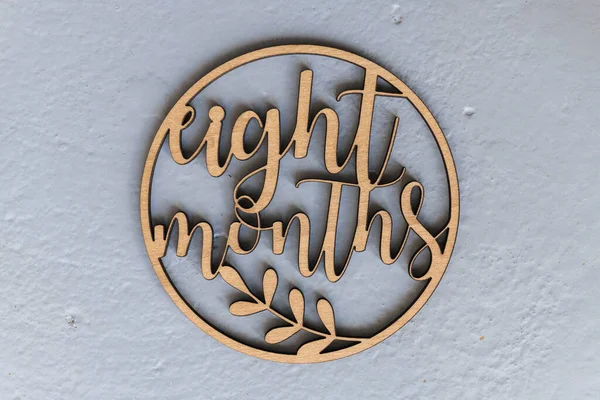 Çocukları fotoğraflamak için gri arka planda uyduları olan açık renkli ahşap bir çember. Sekiz ay.