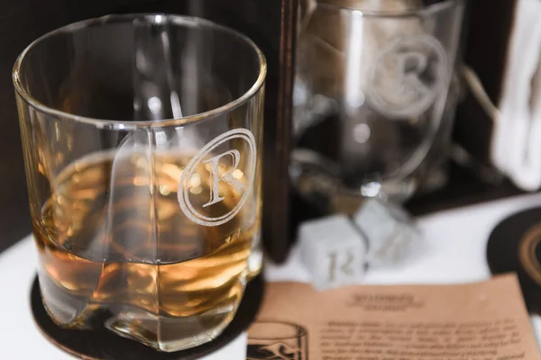 Szklanka Szklana Grawerem Wypełnionym Whisky Białym Stole Skupić Się Szkle — Zdjęcie stockowe