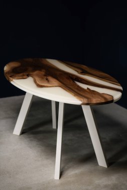 Doğal ahşaptan yapılmış büyük ve pahalı bir masa ve beyaz metal bacaklı beyaz epoksi.