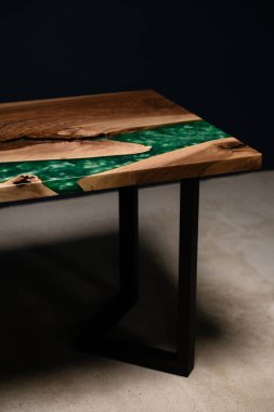Doğal ahşap ve yeşil epoksiden yapılmış bir masanın dikey fotoğrafı