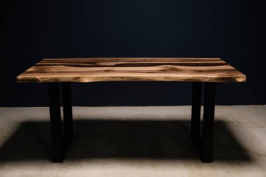 Metal bacaklarında kırmızı epoksi reçine olan büyük ahşap masa.