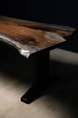 Siyah arka planda doğal ahşaptan yapılmış büyük pahalı el yapımı bir masa.