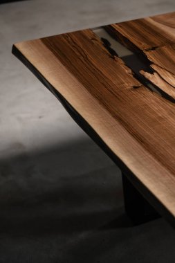 Katı ahşaptan ve şeffaf epoksiden yapılmış büyük pahalı bir masa.