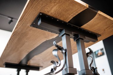 Ahşap ve siyah epoksi reçineden yapılmış masa işlenmiş metal bacaklar üzerinde.