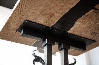 Ahşap ve siyah epoksi reçineden yapılmış masa işlenmiş metal bacaklar üzerinde.