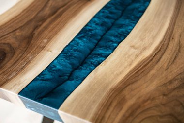 Doğal ahşaptan ve mavi epoksiden yapılmış bir masa.