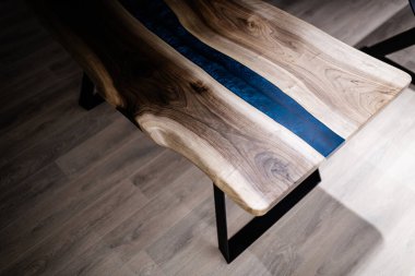 Doğal ahşaptan ve mavi epoksiden yapılmış bir masa.