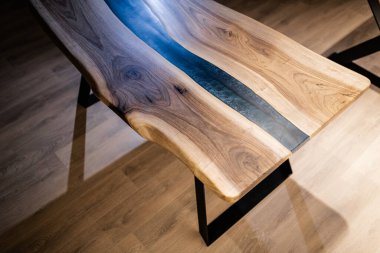 Doğal ahşaptan ve mavi epoksiden yapılmış bir masa.