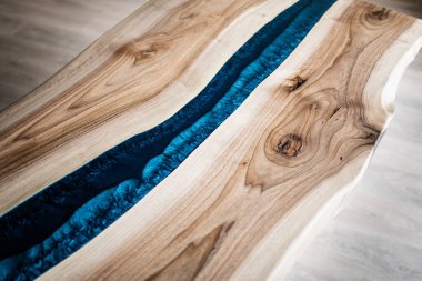 Doğal ahşaptan ve mavi epoksiden yapılmış bir masa.