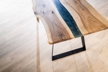 Doğal ahşaptan ve mavi epoksiden yapılmış bir masa.