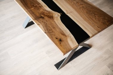 Doğal ahşaptan ve siyah epoksiden yapılmış bir masa.