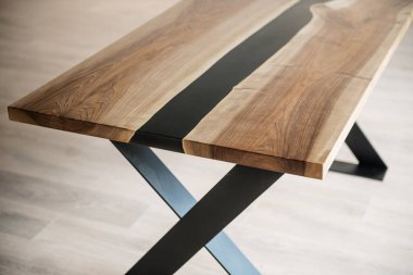 Doğal ahşaptan ve siyah epoksiden yapılmış bir masa.