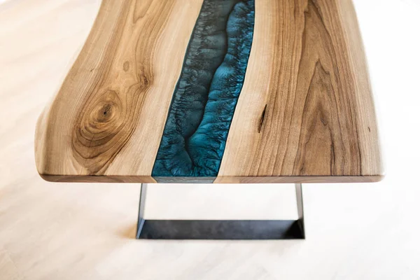 Doğal ahşaptan ve mavi epoksiden yapılmış bir masa.
