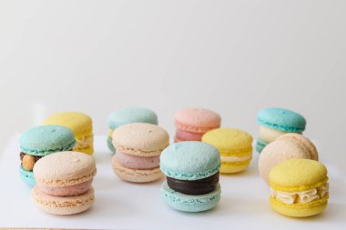 Beyaz arka planda farklı renkte taze badem kurabiyeleri.