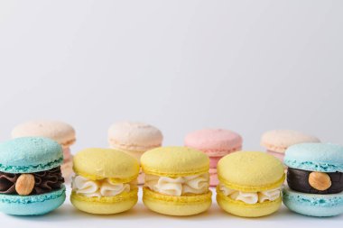 Beyaz arkaplanda düzenlenmiş bir sürü renkli badem kurabiyesi.