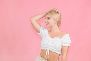 Çok güzel bir genç kız pembe bir arka planda duygularıyla poz veriyor.