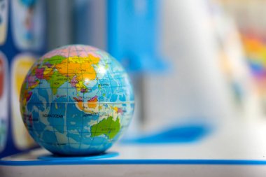 A blue toy globe rests on a student's desk. used as teaching aids in kindergarten