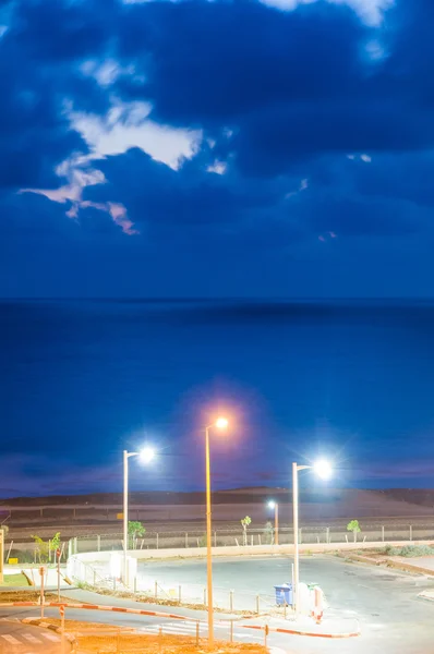 Ночной вид на море с тремя разноцветными электрическими столбами — стоковое фото