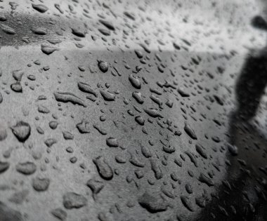 Koyu gri metalik yüzeyde su damlacıkları.