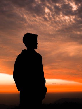 Akşam gökyüzüne karşı duran bir adamın silüeti..