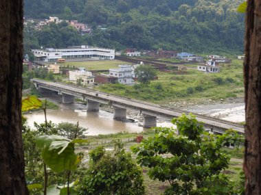 Yayın tarihi: 25 Ağustos 2021: dehradun uttarakahnd India. Kuzey Hindistan 'daki bir nehrin üzerindeki beton köprünün geniş açılı görüntüsü. Ön planda ağaçlarla tepeden çekilmiş..