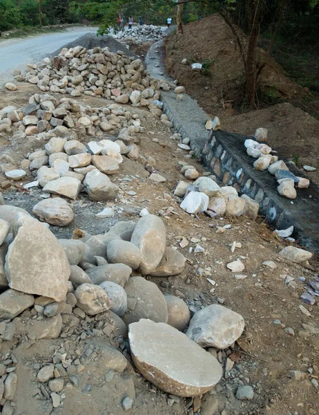 A pile of stone alongside road for constructing a stone retaining wall to prevent landslide and cutting. Uttarakhand India.