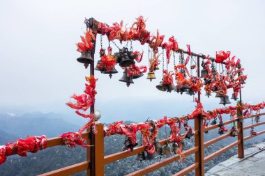 A wide angle shot of hanging bells with holy red cloths with a snow covered mountains in the Background, Kartik Swami Temple, Rudraprayag Uttarakhand ,India. clipart