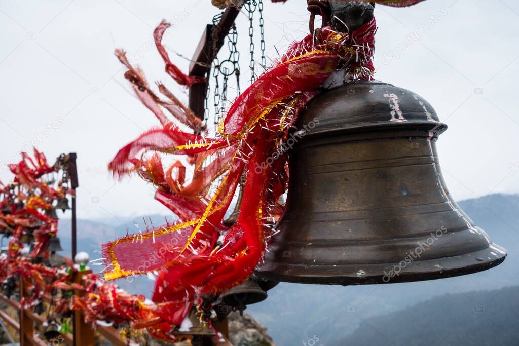 A closeup shot of hanging bells with holy red cloths with a snow covered mountains in the Background, Kartik Swami Temple, Rudraprayag Uttarakhand ,India.