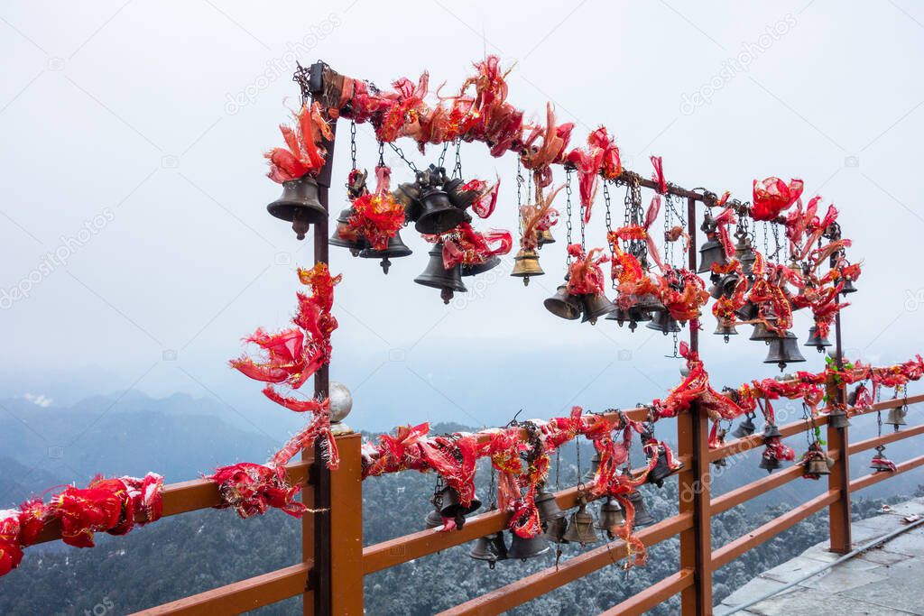 A wide angle shot of hanging bells with holy red cloths with a snow covered mountains in the Background, Kartik Swami Temple, Rudraprayag Uttarakhand ,India.