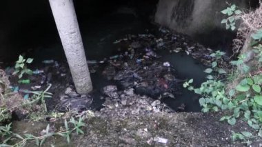 A gutter full of plastic and toxic waste flowing in open.