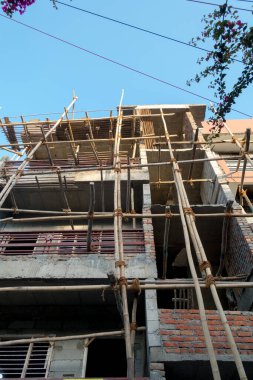March 25th 2022. dehradun INDIA. An under construction multiple story building with support logs and climbing ropes.