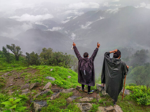 September 21st 2021 Uttarakhand INDIA. Hikers with backpacks and walking sticks with raincoats on a Himalayan trek Summit celebrating.