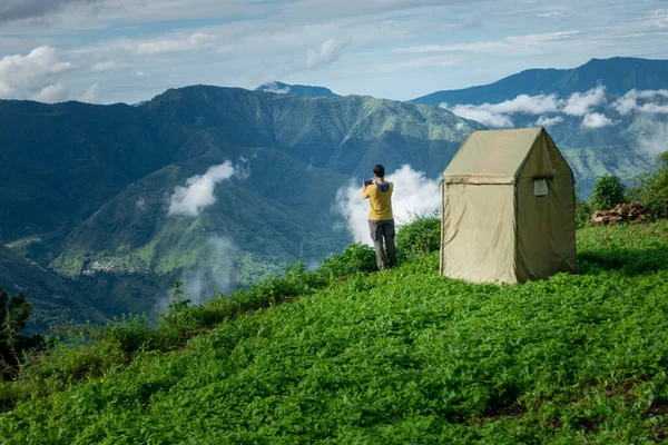 Uttarakhand India. A man camping and taking a photograph of the valley landscape