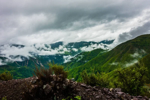 Hills in the Himalayas with green trees covered in mist and white clouds after a rainfall. Uttarakhand India.