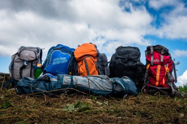 September 16th 2021. Uttarakhand India. Colorful backpacks of hikers in line in the meadows of Himalayas with landscapes in the background.