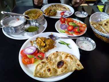 Hint yemeği Kadhai paneer, Hint tereyağı roti, baharatlı lor, yeşil salata ile servis edilir. Yeni Delhi 'de bir restoran..