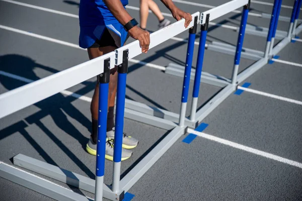 Joven endereza los obstáculos alineados a través de una pista de atletismo — Foto de Stock