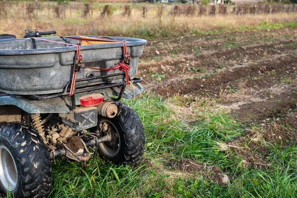 Closeup of hauling bin strapped to a farm ATV by a new garden — Stock Photo, Image