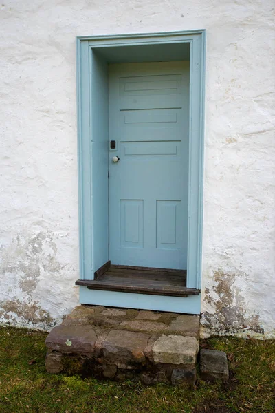 Niebieskie kolonialne drewniane drzwi w bielone kamienny domek z rustykalnymi schodami — Zdjęcie stockowe
